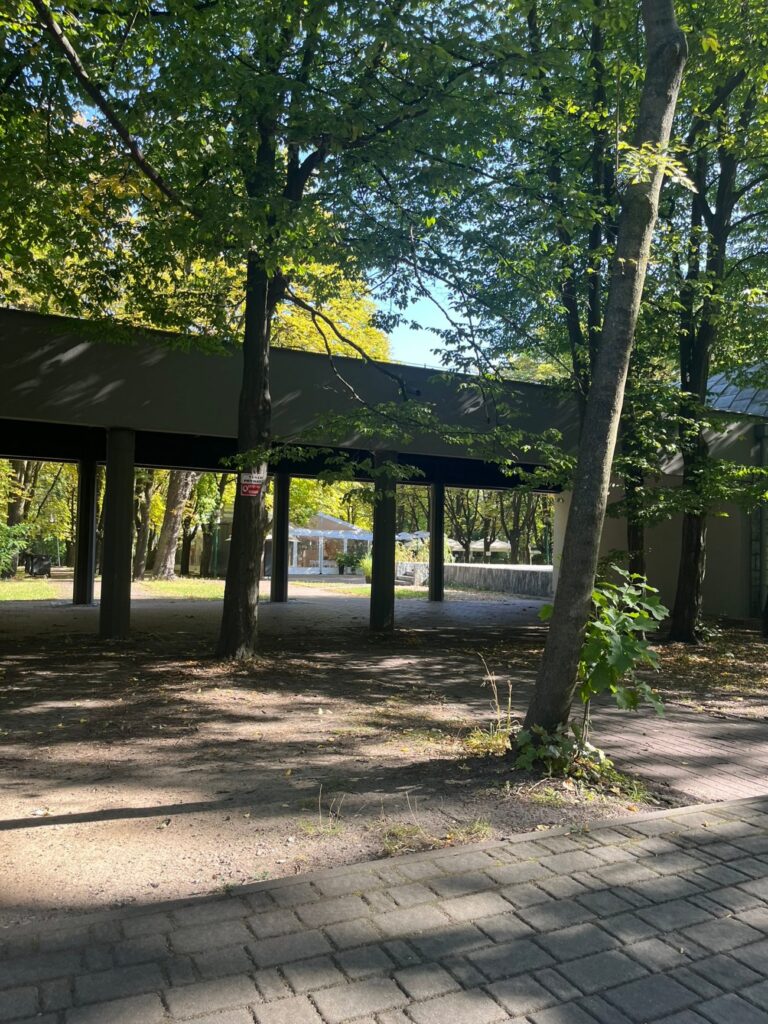 Zadaszony pawilon na betonowych słupach, przed nim utwardzony plac i chodnik z kostki brukowej.