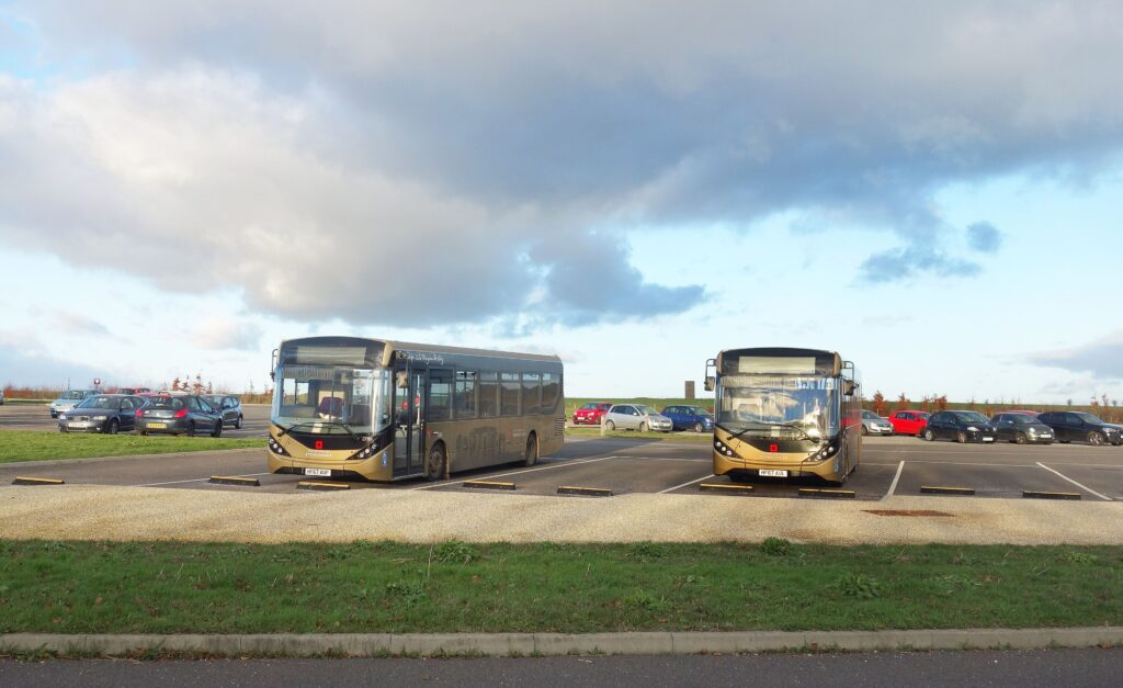 Dwa niskopodłogowe busy wahadłowe na parkingu przy centrum dla zwiedzających Stonehenge